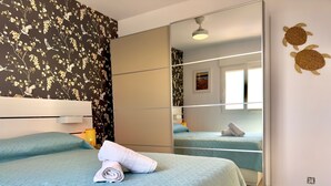 Une chambre d’hôtel avec un grand lit, un miroir et un mur recouvert d’un papier peint à motifs floraux.
