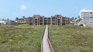 A modern building with a central courtyard, surrounded by a wooden boardwalk. - 2-Bedroom Beachfront Comfort w/ Heated Pool! (South Padre Island)