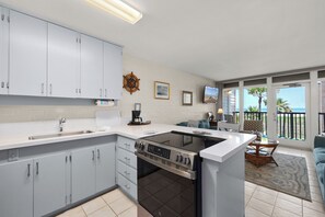 Een moderne keuken met een centraal eiland, een ingebouwde oven en een eethoek met uitzicht op de oceaan.