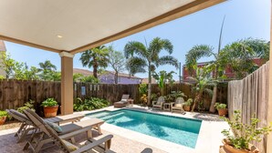 A backyard with a swimming pool, lounge chairs, and potted plants. - Beautiful Coastal Sol Villa • Heated Pool • 3 Min Walk to Beach (South Padre Island)