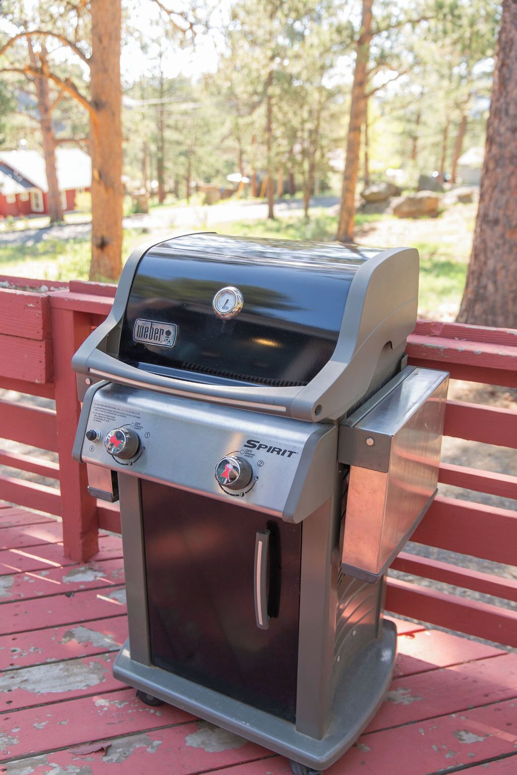 Un barbecue Spirit portable doté d’un écran numérique, posé sur un banc en bois rouge dans un parc.