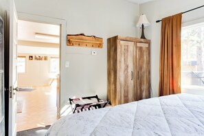 Une chambre à coucher avec un lit, une armoire en bois et un porte-manteau.