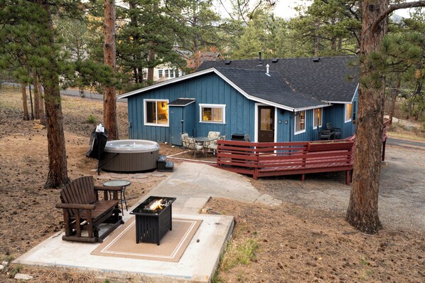 Une cabane avec un bain à remous, un espace salon extérieur et un foyer.