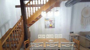 Een eetgedeelte met een houten trap, witte stoelen en een tafel.