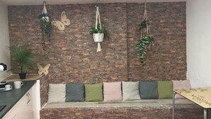 Een gezellig zitgedeelte met een bakstenen muur, een houten bank met kussens en hangplanten.