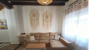 Een woonkamer met een beige modulaire bank, een houten salontafel en twee droomvangers aan de muur.