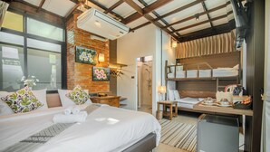 Une chambre d’hôtel avec un grand lit, un bureau avec un ordinateur, un petit réfrigérateur, une douche et un lit superposé avec des serviettes.