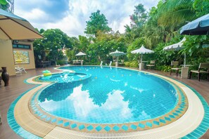 Een buitenzwembad, parasols bij het zwembad en ligstoelen