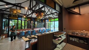 Un restaurant avec un long comptoir, des chaises bleues et un espace buffet.