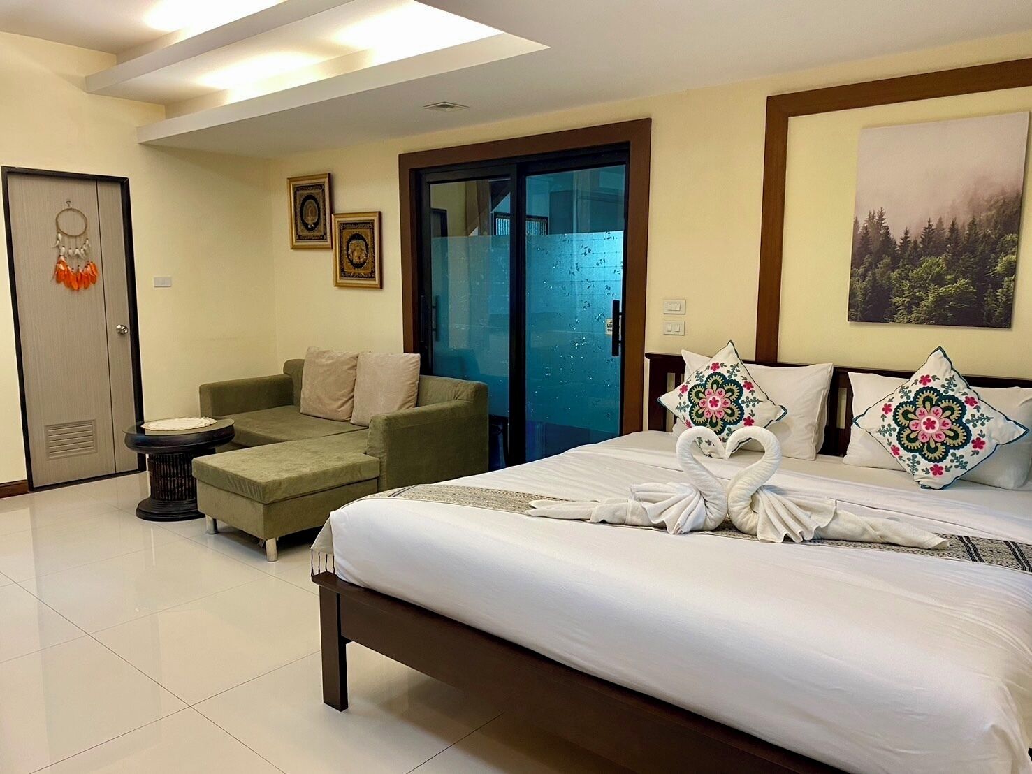 A hotel room with a bed, a sofa, a small table, a door, and a window.