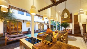 Amplio espacio interior con piscina, muebles de madera y lámparas colgantes.