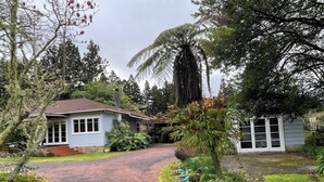 Ein Haus mit befestigter Auffahrt, die zu einer Haustür führt, umgeben von üppigem Grün und Bäumen.