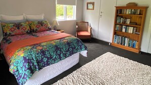 Ein Schlafzimmer mit einem Bett, einem Sessel, einem Bücherregal und einem Fenster.