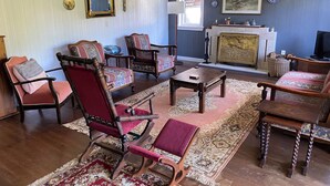 Ein traditionelles Wohnzimmer mit antiken Möbeln, einem Kamin und dekorativen Tellern an der Wand.