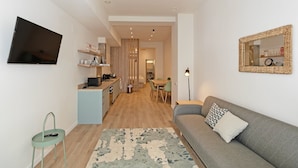 Ett kompakt bostadsutrymme med ett litet kök, en matplats och en sittgrupp med en soffa och ett soffbord.