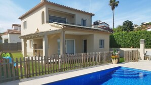 Une maison à deux étages avec une piscine, une clôture en bois et un jardin.