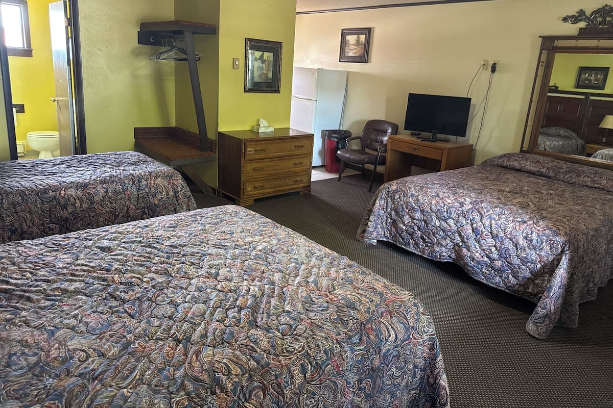 A hotel room with two beds, a desk, a chair, a television, and a mirror.