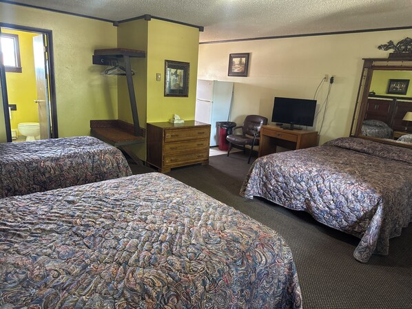 A hotel room with two beds, a desk, a chair, a television, and a mirror.
