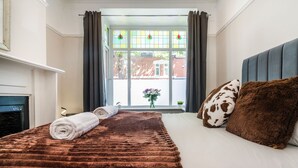 A neatly made bed with a brown blanket, a rolled white towel, and a brown and white spotted pillow. - Cosy 4-Bed - Sleeps 7, Garden (Birmingham)