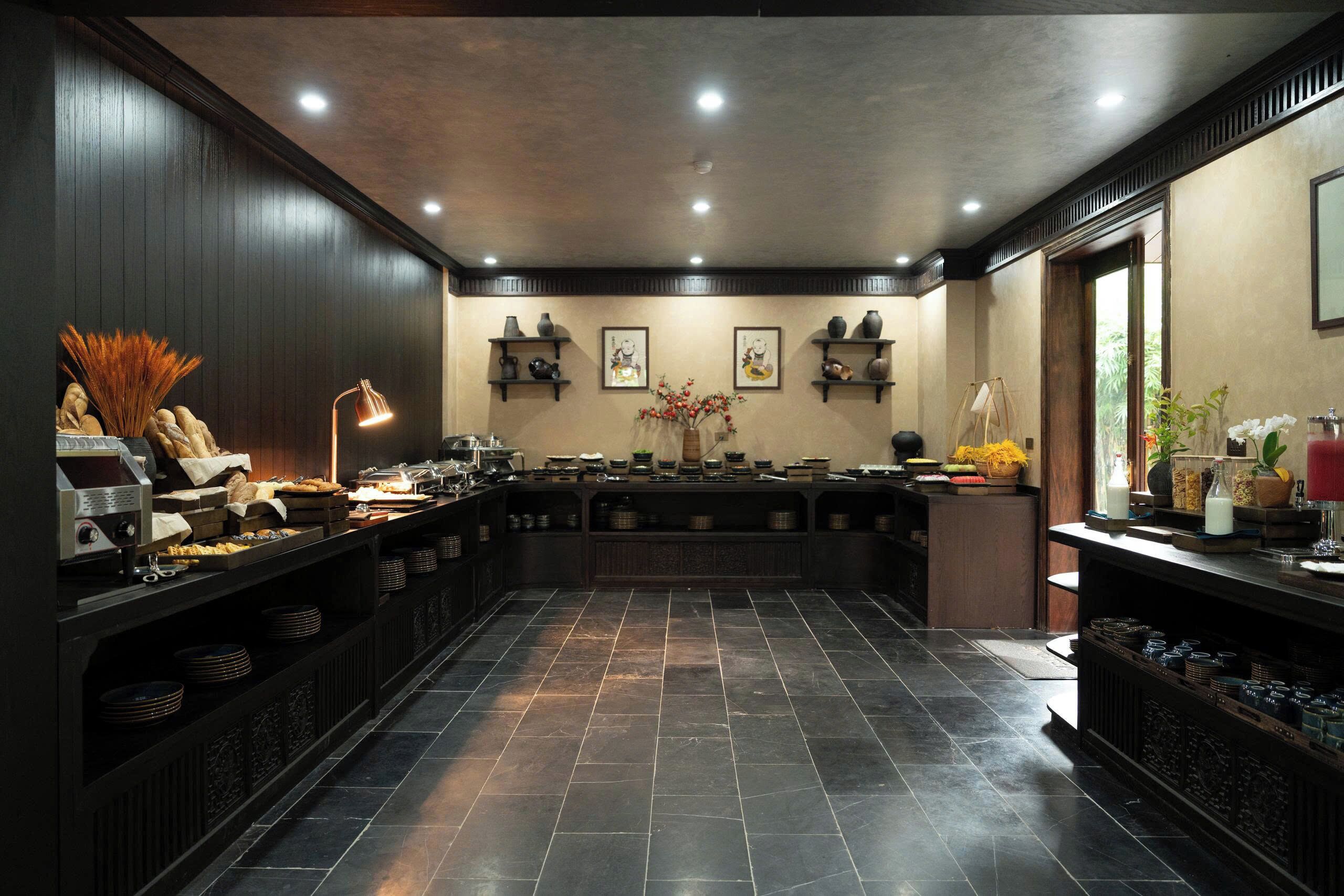 A spacious kitchen with dark wood paneling, a central island with various kitchen items, and a tiled floor.