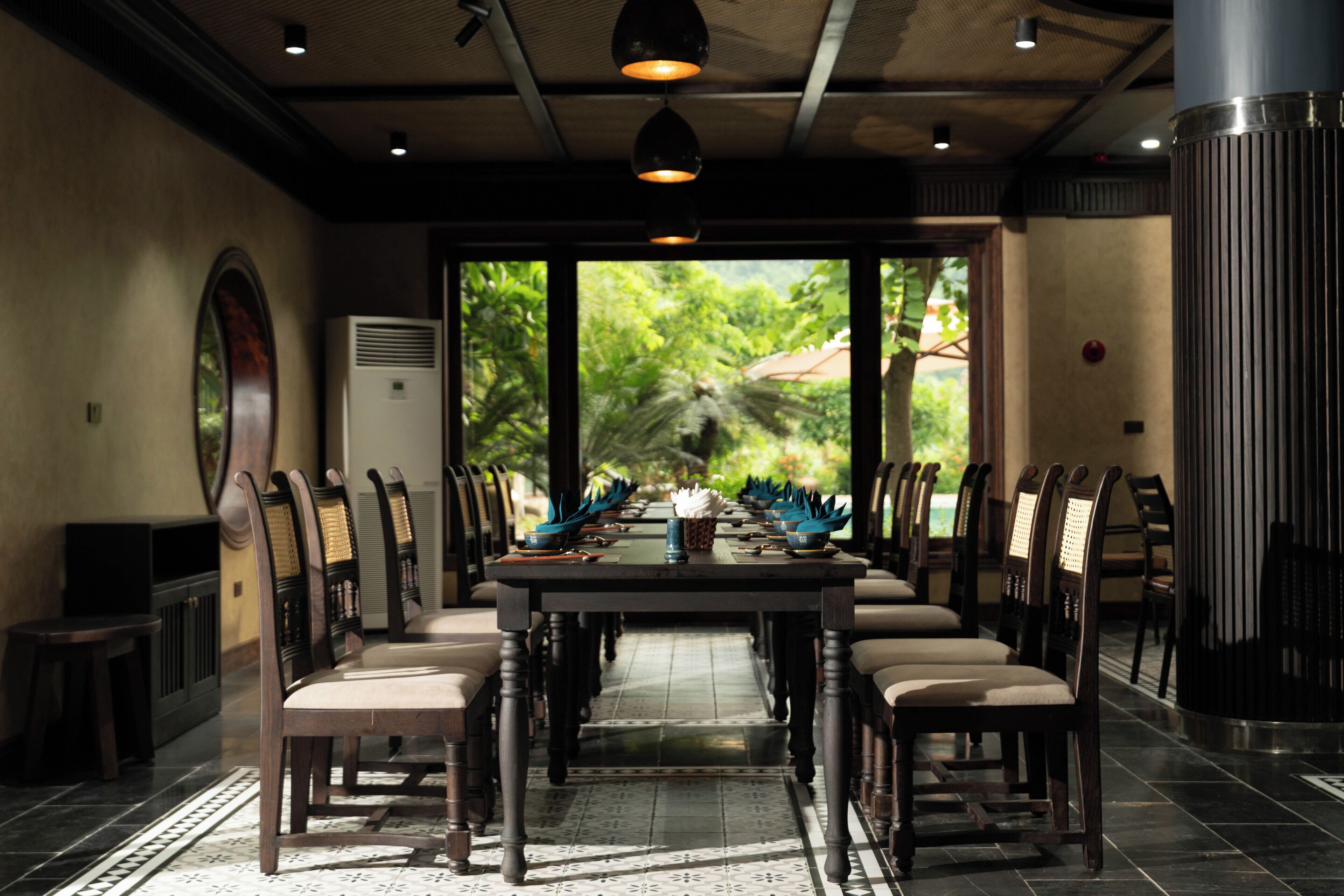 A conference room with a long table, chairs, and a view of greenery outside.
