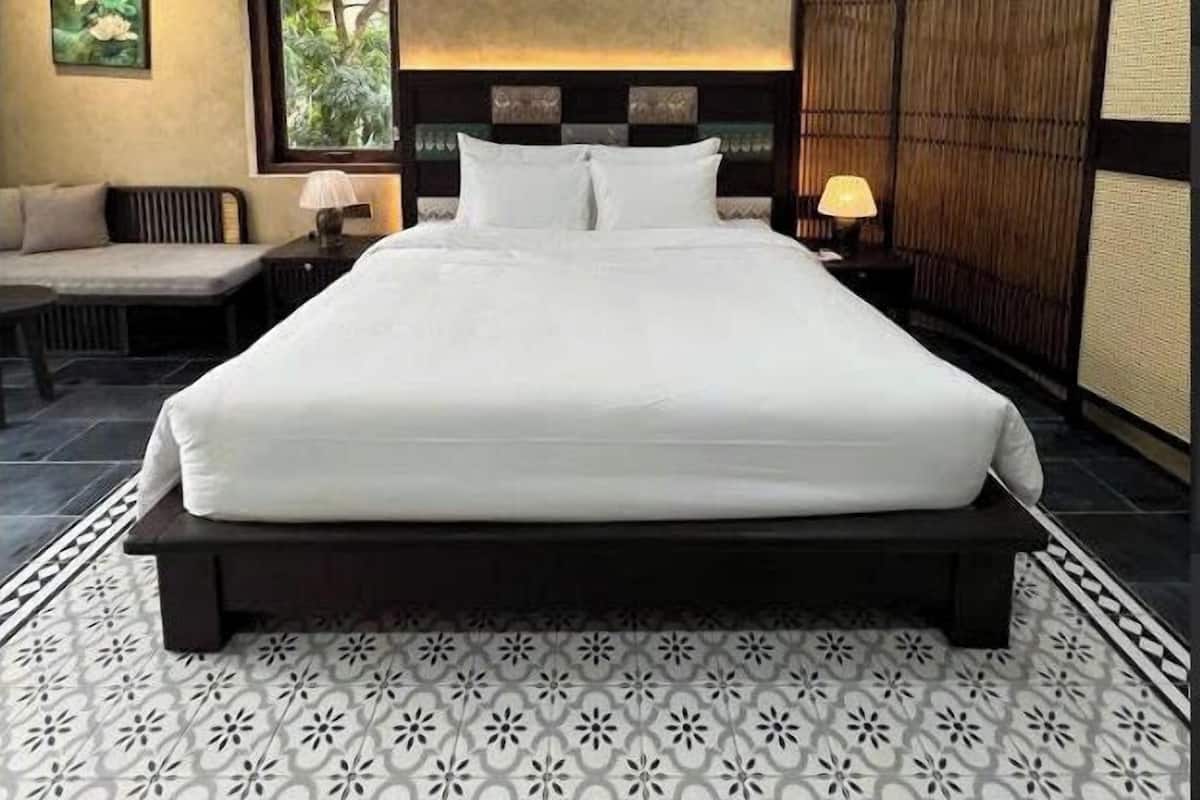 Un dormitorio ordenado con una cama grande, un sofá y una ventana.