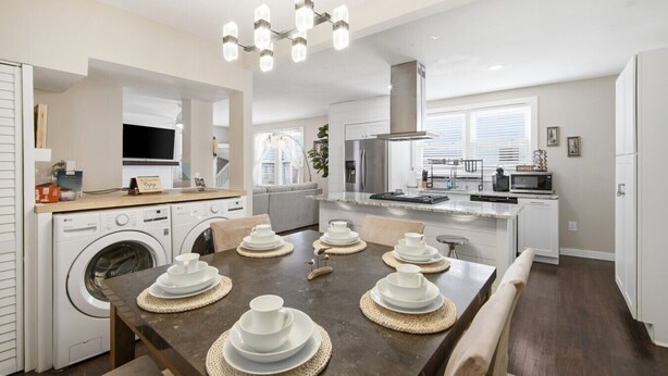 A modern kitchen with a dining area, built-in appliances, and a large window.