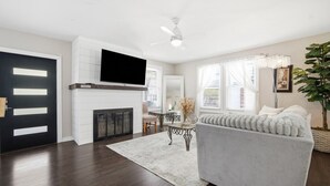 A living room with a fireplace, a sofa, a TV, and a dining area.