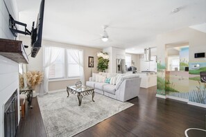 A modern living room with a sofa, coffee table, and a view into the kitchen. - Modern Bayside 4BR | Walk to Beach & Boardwalk (Ventnor City)