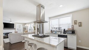 A modern kitchen with a central island, bar stools, a built-in oven, and a microwave.