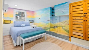 Een slaapkamer met een bed, een bankje en een muurschildering van een strand.