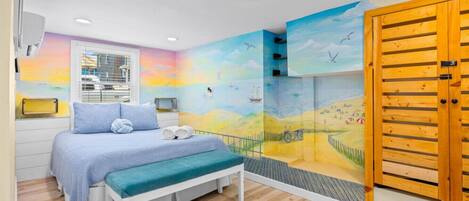 Een slaapkamer met een bed, een bankje en een muurschildering van een strand.