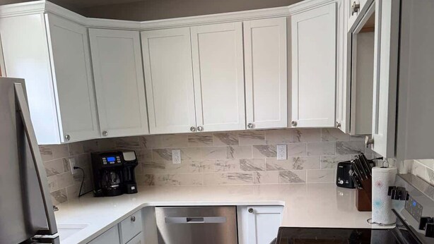 A modern kitchen with white cabinets, a stainless steel refrigerator, a dishwasher, and a stove. - The Spruce House  Family 4BR 2 Bath, Great Location, In Ogallala, Close to Lake McConaughy (Ogallala)