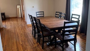 A dining room with a wooden table and chairs, a ceiling fan, and a window with curtains. - The Spruce House  Family 4BR 2 Bath, Great Location, In Ogallala, Close to Lake McConaughy (Ogallala)