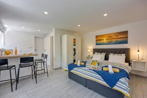 Een moderne slaapkamer met een bed, nachtkastjes, een bureau met stoelen en een schilderij aan de muur.