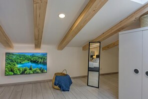 A room with a large TV on the wall, a wooden ceiling, a bean bag chair, and a wardrobe.