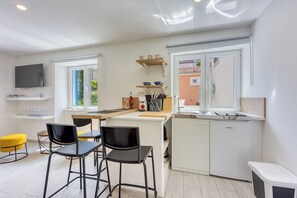 A modern kitchen with a dining area, a TV, and a window.