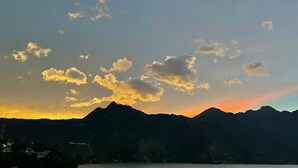 A mountain range silhouette against a sunset sky with clouds.
