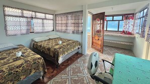 A room with two beds, a fan, and a window with a view.