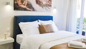 Un dormitorio con una cama grande, una mesita de noche, un cuadro colgado en la pared y una ventana con cortinas.