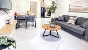 Una sala de estar moderna con un sofá gris, una mesa de centro de madera y un comedor con mesa y sillas.