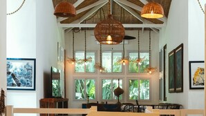 A spacious interior with high ceilings, exposed beams, and hanging light fixtures. - Casa Azul · Family Retreat & Caribbean Charm (Manzanillo)