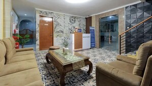 A hotel lobby with a reception desk, a staircase, and seating areas.