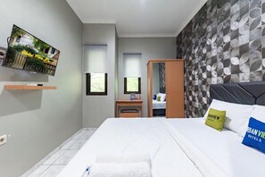 Una habitación de hotel con una cama, un escritorio, un televisor y un armario.