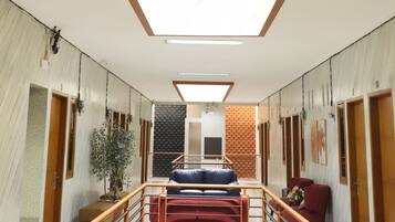 Un moderno vestíbulo de hotel con una escalera central, un mostrador de recepción y un techo alto con tragaluces.