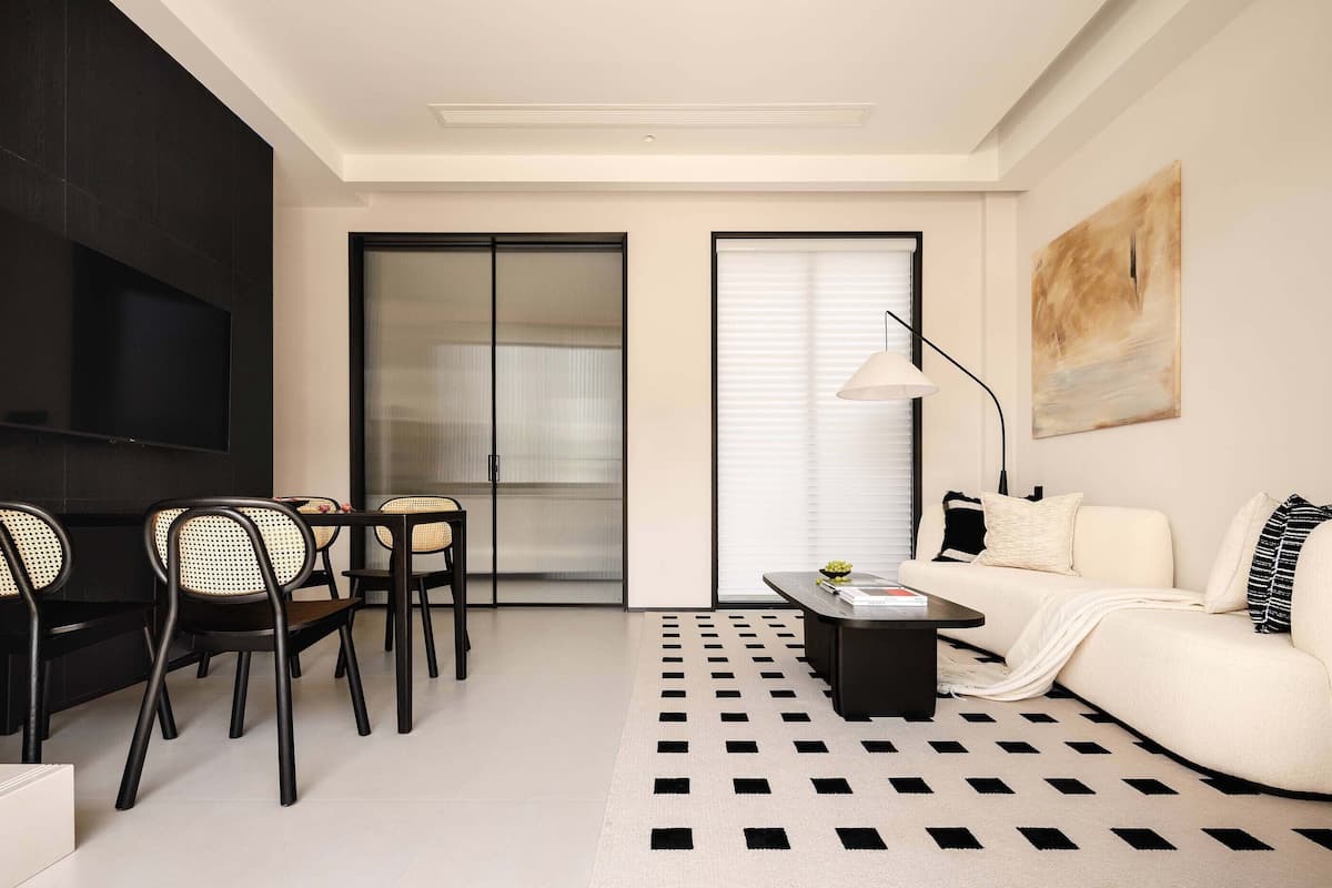 A modern living room with a sofa, chairs, a coffee table, and a TV.