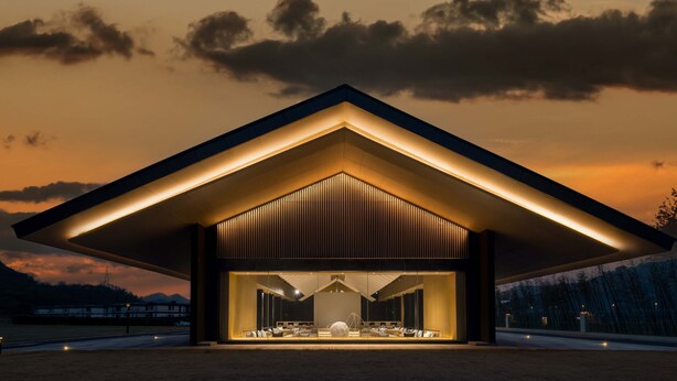 Un edificio moderno con una entrada grande e iluminada y vistas del paisaje circundante.