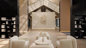 Un interior moderno con una pieza de arte central, zona de estar y estanterías.