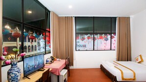 A hotel room with a bed, a desk with a computer, a small table, a TV, and a window with curtains. - The Rice Hotel & Tour - 195 De Tham (Ho Chi Minh City)