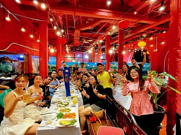 Un grupo de personas cenando en un restaurante con paredes rojas y techos a la vista.